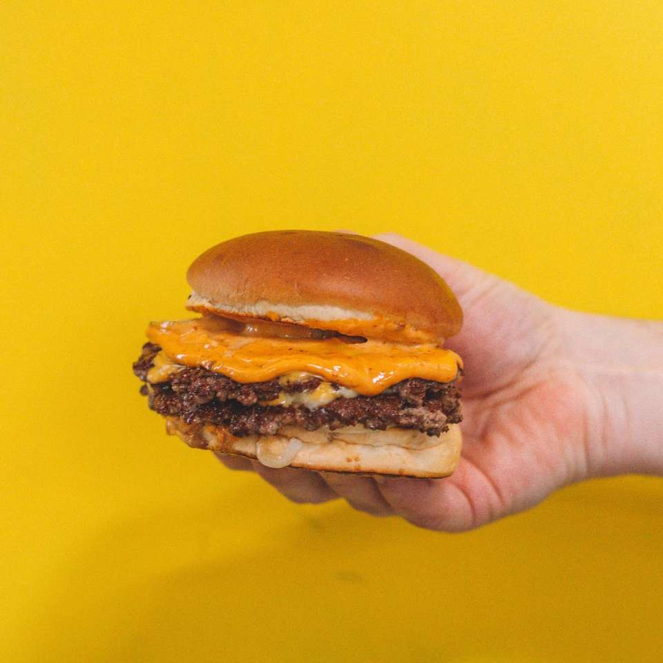 személy tartja a hamburgert pogácsával online puzzle