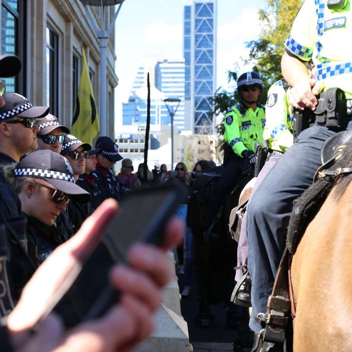 黒のスマートフォンを保持している黒の警察の制服を着た男 スライディングパズル・オンライン