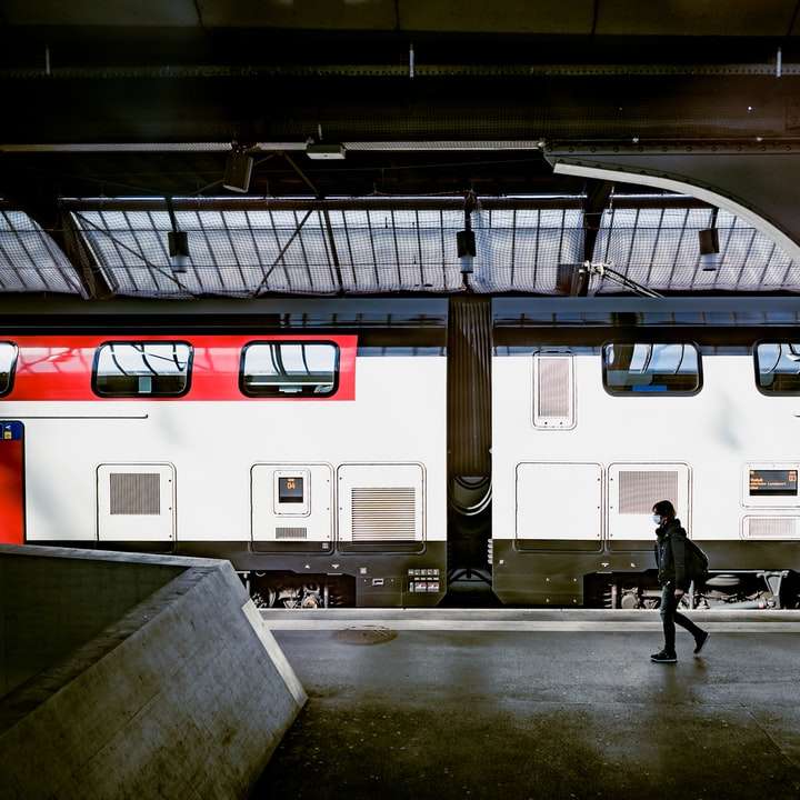 Hombre con chaqueta negra caminando cerca del tren blanco rompecabezas en línea
