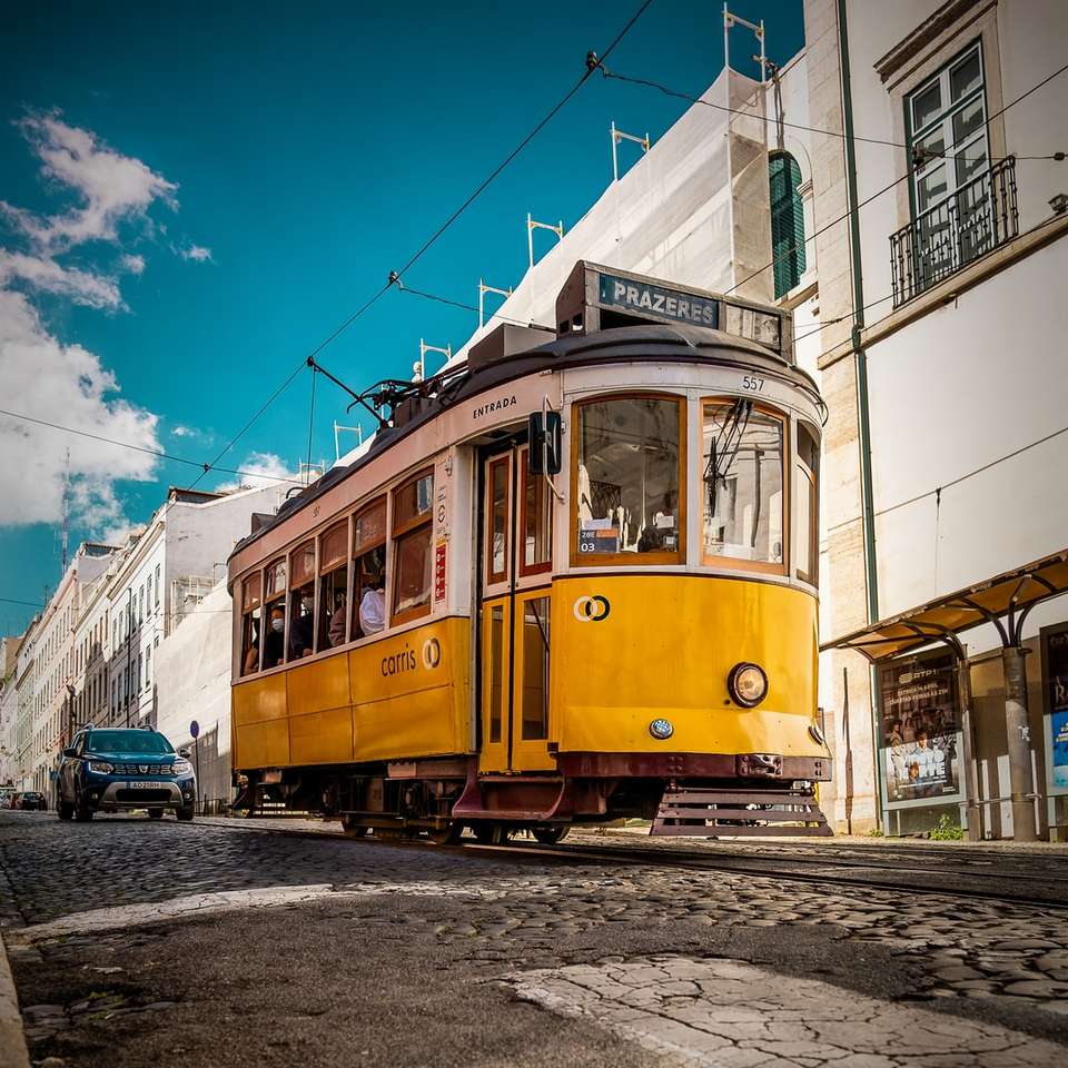żółty i biały tramwaj na drodze w pobliżu białego betonowego budynku puzzle online