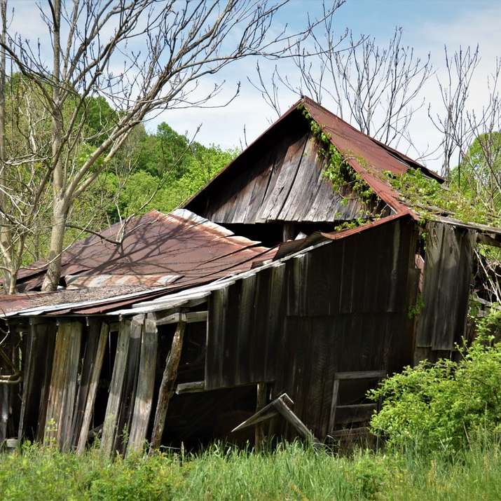 casa di legno marrone vicino al campo di erba verde durante il giorno puzzle scorrevole online