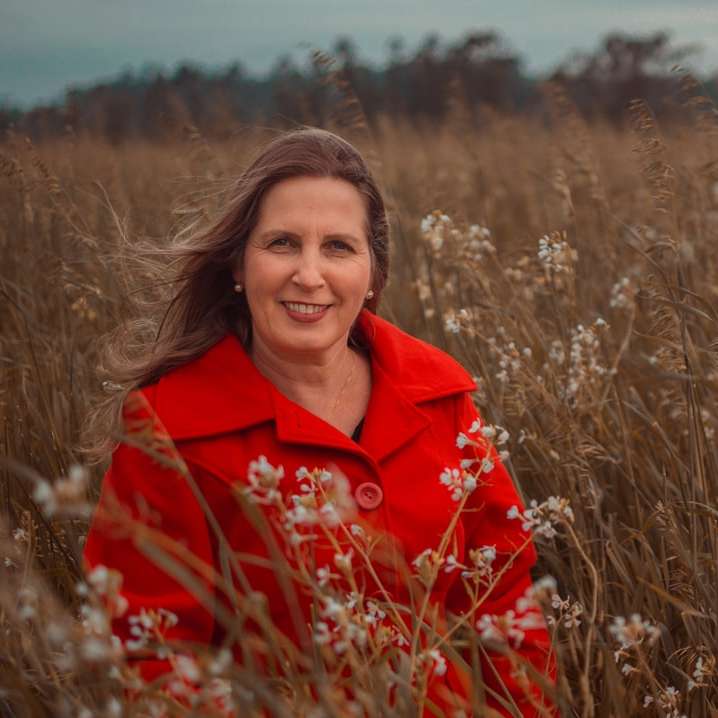 kobieta w czerwonym płaszczu stojąca na brązowym polu trawy puzzle online