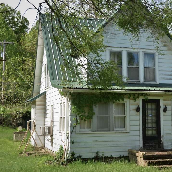Biały drewniany dom w pobliżu zielonego drzewa w ciągu dnia puzzle przesuwne online