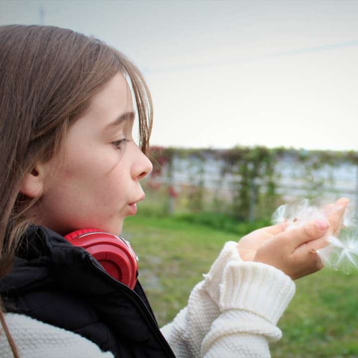 dívka v bílém pleteném šátku drží bílý květ pampelišky online puzzle