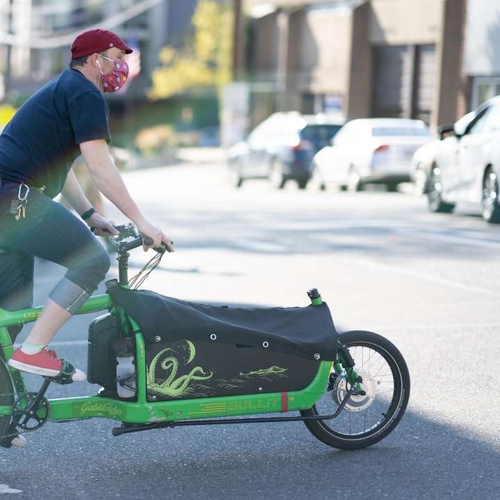 мъж в синя и червена риза, каращ зелен велосипед плъзгащ се пъзел онлайн