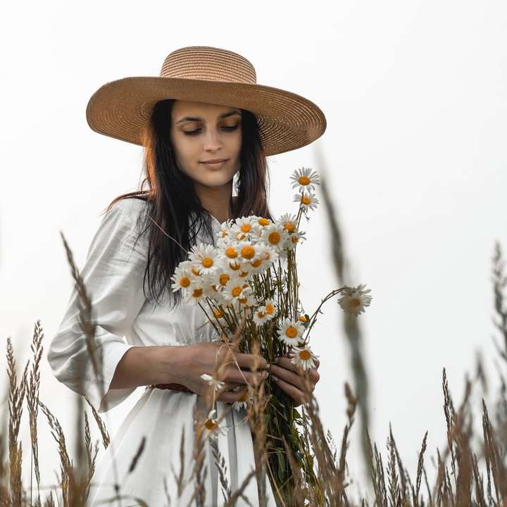 femeie în cămașă albă cu mânecă lungă, ținând flori albe alunecare puzzle online