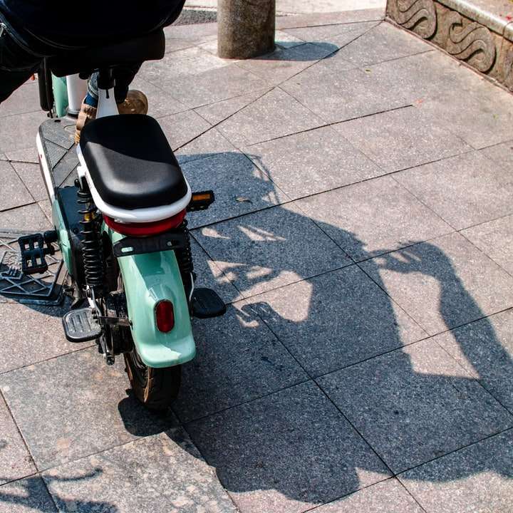 persona in giacca nera che guida uno scooter bianco e verde puzzle online