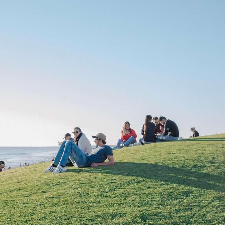 άνθρωποι που κάθονται στο πράσινο γρασίδι κατά τη διάρκεια της ημέρας συρόμενο παζλ online