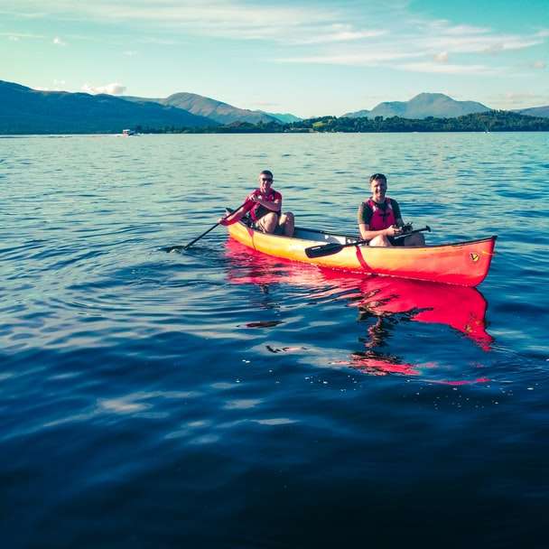 2 personnes à cheval sur un kayak rouge sur une mer bleue pendant la journée puzzle coulissant en ligne
