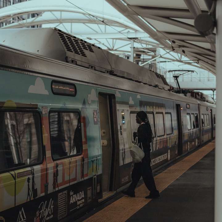 白い電車の横に立っている黒いジャケットの男 オンラインパズル