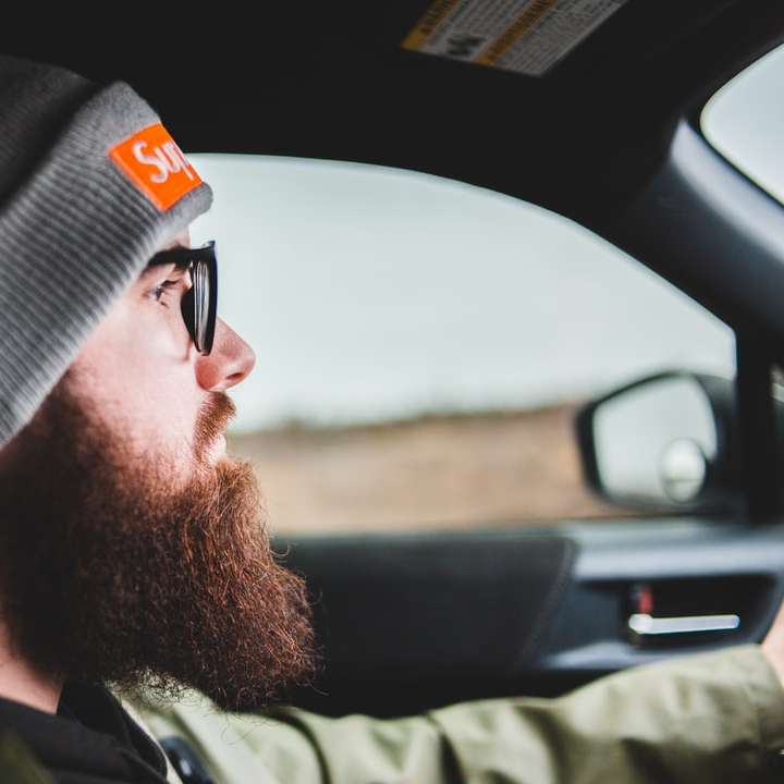 muž v černé pletené čepici a černých slunečních brýlích řídí auto posuvné puzzle online