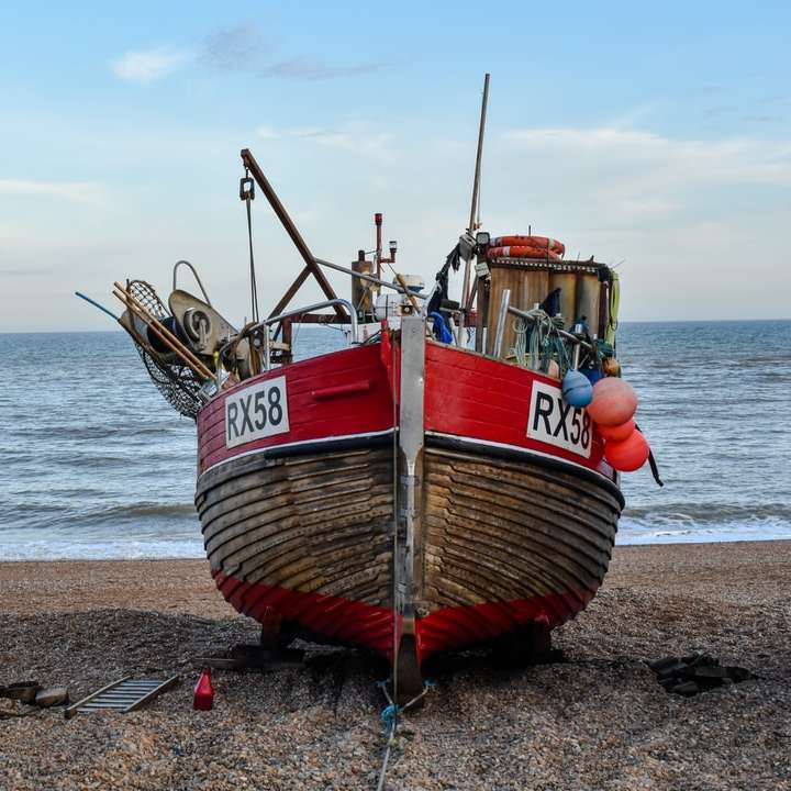 hnědá a červená loď na pláži během dne online puzzle