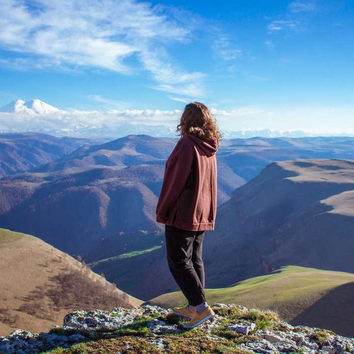 жінка в коричневій куртці, стоячи на скелі розсувний пазл онлайн