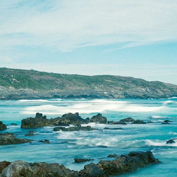 rotsachtige kust onder blauwe hemel overdag schuifpuzzel online