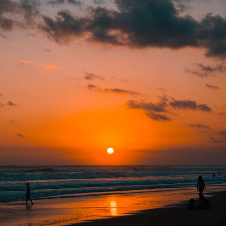 silhueta de pessoas na praia durante o pôr do sol puzzle online