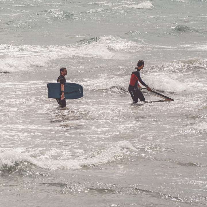muž v černém a červeném neoprenu s modrým surfovacím prknem online puzzle