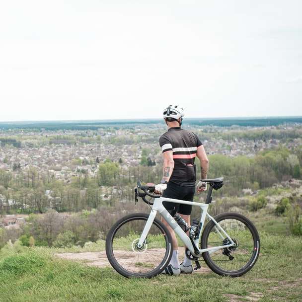 Mann im schwarzen Hemd, das Fahrrad auf grünem Grasfeld reitet Schiebepuzzle online