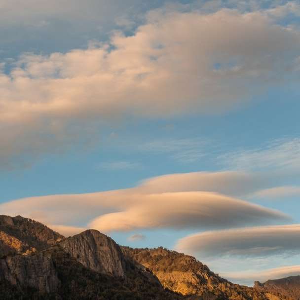 Brązowe i szare góry pod białymi chmurami i błękitne niebo puzzle przesuwne online