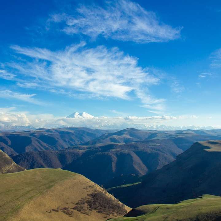 кафяви и зелени планини под синьо небе през деня онлайн пъзел