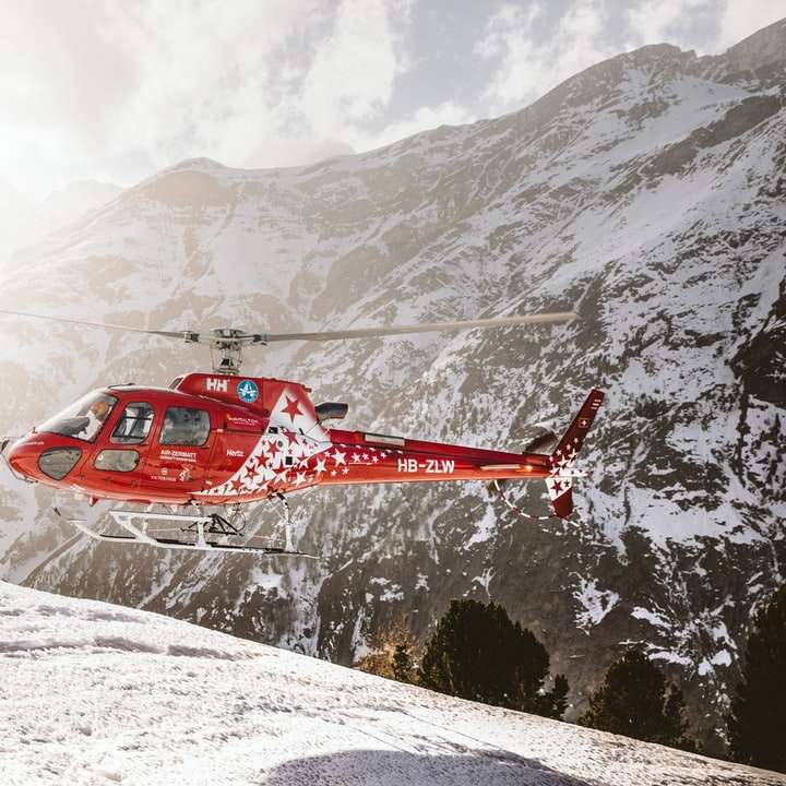 Hélicoptère rouge survolant la montagne couverte de neige puzzle coulissant en ligne