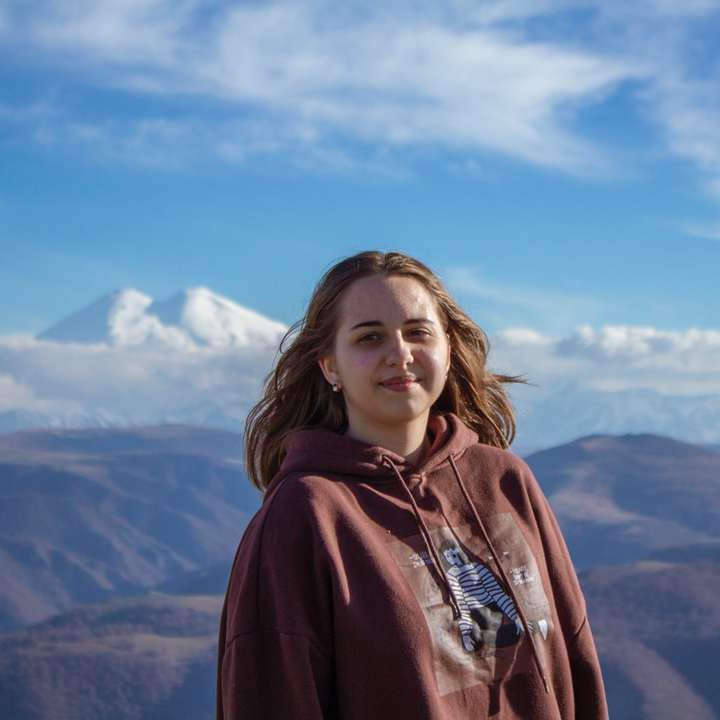 жінка в червоній балахоні, стоячи на вершині гори розсувний пазл онлайн