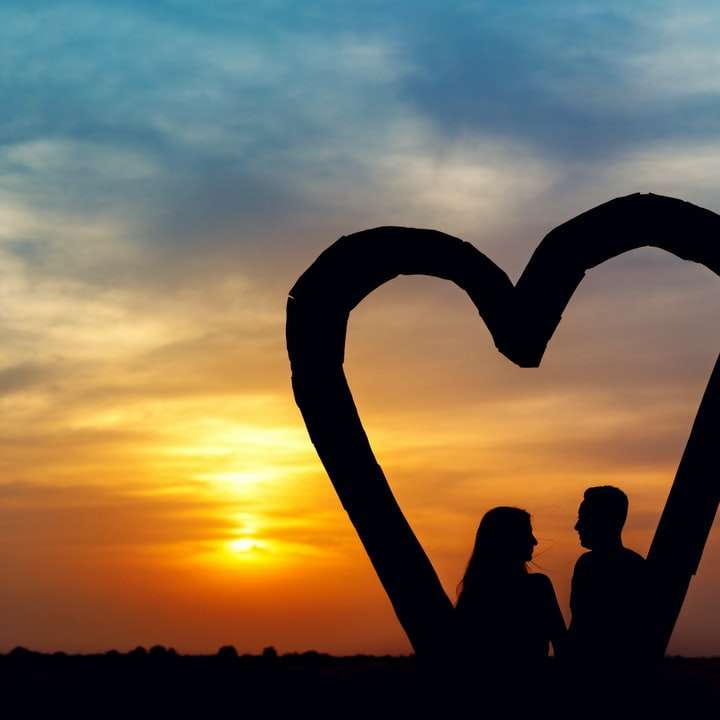 silhouette of 2 people sitting on beach during sunset online puzzle