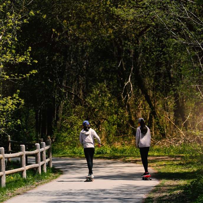 mężczyzna i kobieta spacerują ścieżką między zielonymi drzewami puzzle online