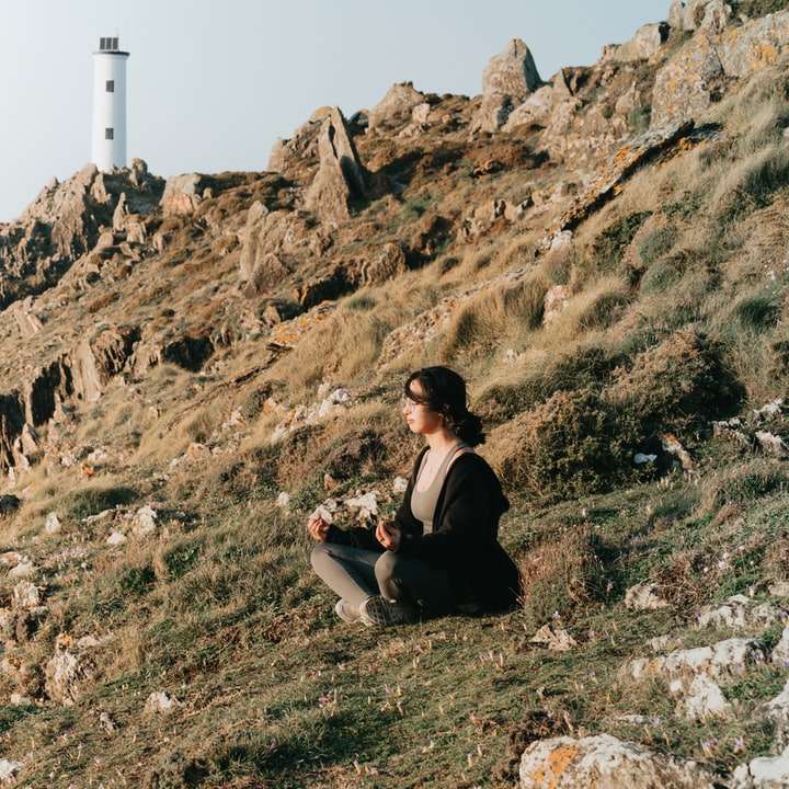 nő fekete kabátban ül a barna szikla hegyen csúszó puzzle online