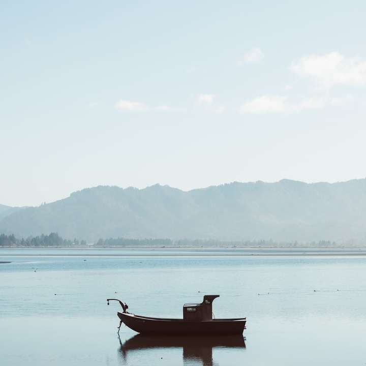 людина катається на човні по озеру в денний час онлайн пазл