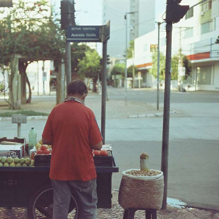 homme en chemise rouge debout près d'un stand de fruits puzzle coulissant en ligne
