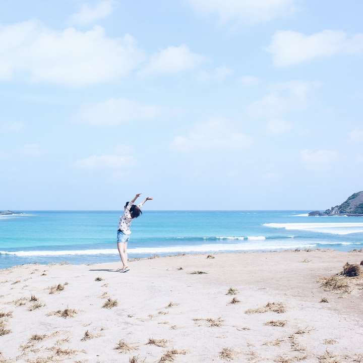 donna in abito bianco e nero in piedi sulla riva della spiaggia puzzle scorrevole online