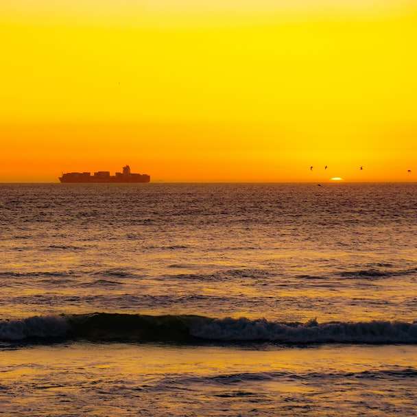 Person, die bei Sonnenuntergang auf Meereswellen surft Schiebepuzzle online