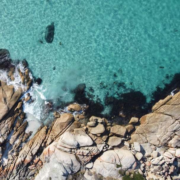 Hnědý skalní útvar na modrém moři během dne posuvné puzzle online
