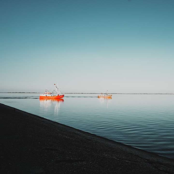 Красная лодка в море под голубым небом в дневное время онлайн-пазл
