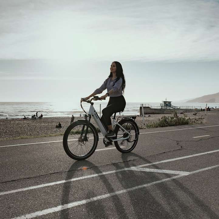 donna in camicia nera a maniche lunghe che va in bicicletta puzzle online