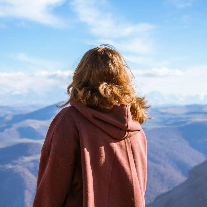 kobieta w brązowej bluzie z kapturem stojąca na szczycie góry puzzle online