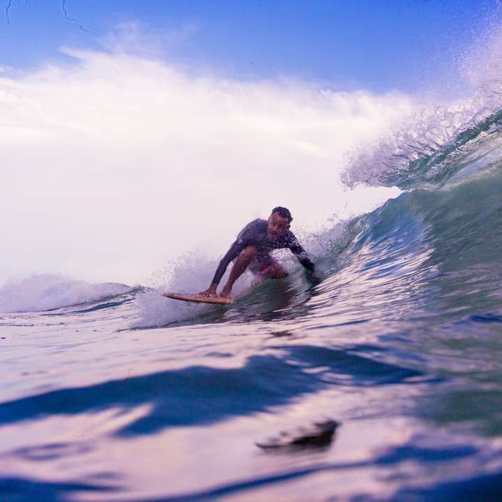 man i vita shorts surfar på havets vågor under dagtid Pussel online