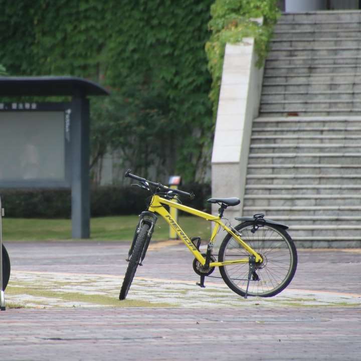 жълт и черен велосипед, паркиран на тротоара през деня плъзгащ се пъзел онлайн