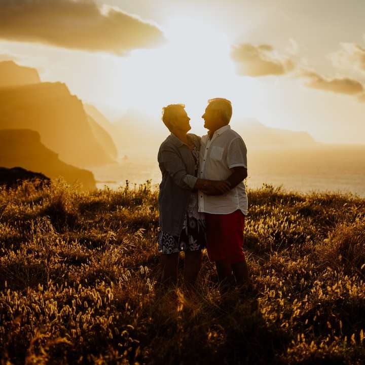 L'homme et la femme debout sur le terrain d'herbe verte pendant le coucher du soleil puzzle en ligne