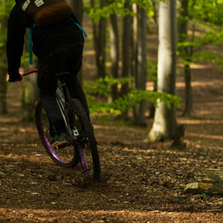 man i svart jacka cyklar på skogen under dagtid glidande pussel online