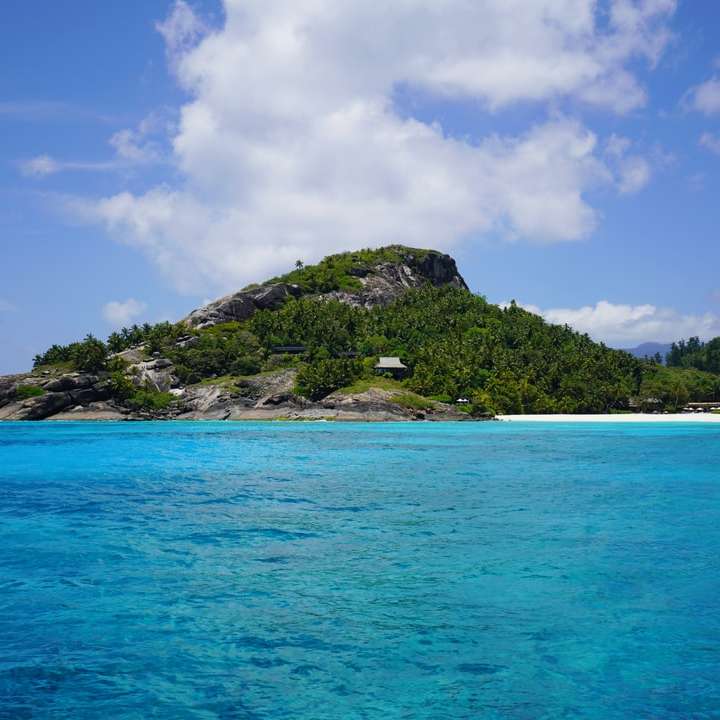 île verte sous ciel bleu et nuages ​​blancs pendant la journée puzzle coulissant en ligne