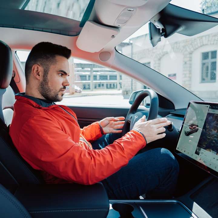 Hombre en camisa roja de manga larga conduciendo un coche rompecabezas en línea
