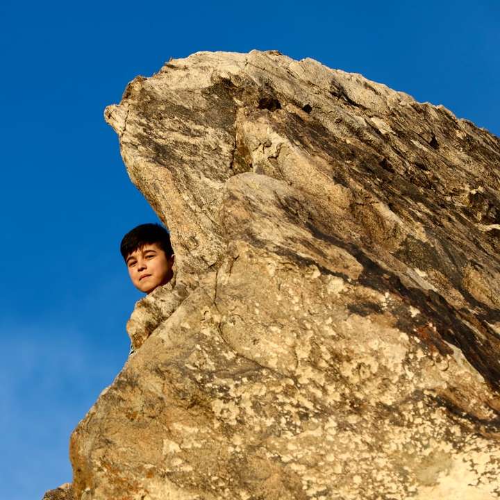жена в кафяво яке, стояща върху скална формация онлайн пъзел