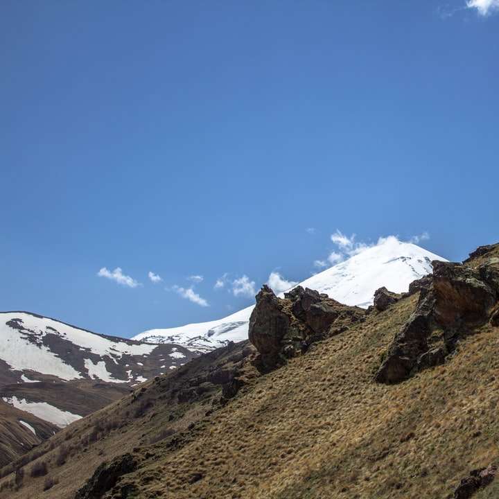 Montaña verde y marrón bajo un cielo azul durante el día puzzle deslizante online