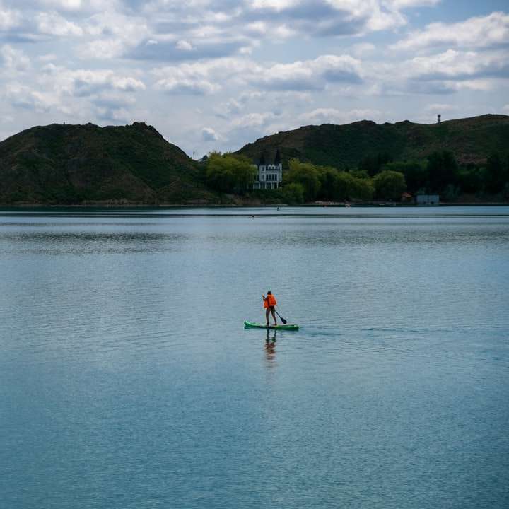 persona che cavalca un kayak rosso su uno specchio d'acqua durante il giorno puzzle online