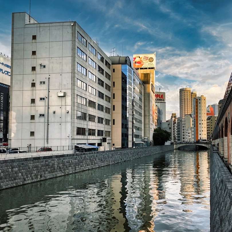 bílá betonová budova poblíž řeky pod modrou oblohou online puzzle