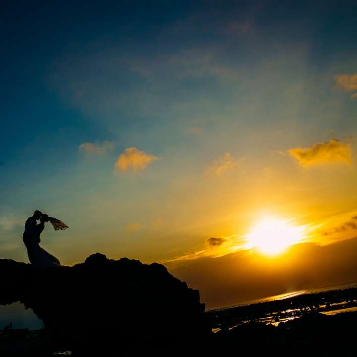 σιλουέτα του ατόμου που στέκεται πάνω σε σχηματισμό βράχου συρόμενο παζλ online