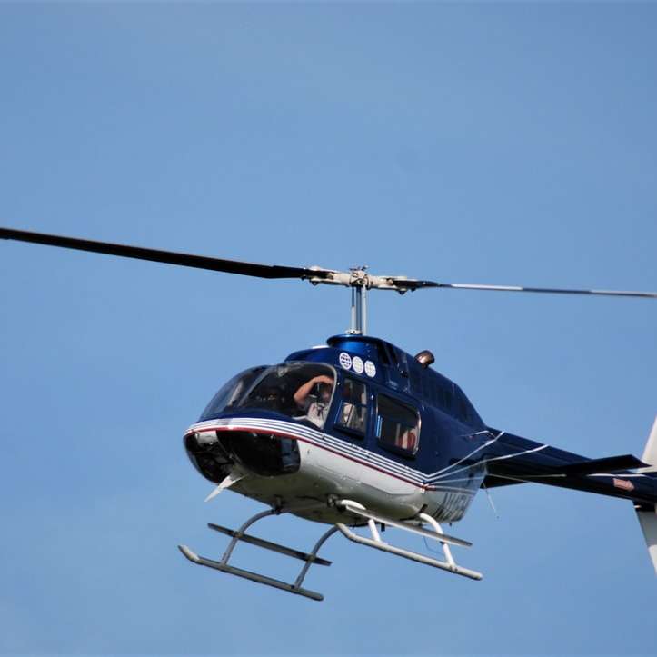 helicóptero azul e branco voando no céu durante o dia puzzle deslizante online