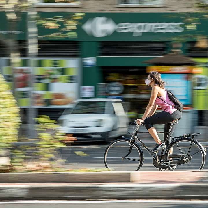 mulher de blusa roxa e branca andando de bicicleta puzzle online