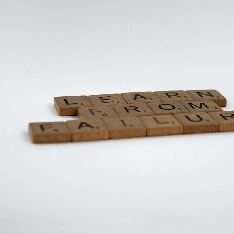 blocchi di lettere in legno marrone su superficie bianca puzzle online